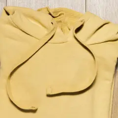 Żółta bluza z kapturem złożona na drewnianym tle.