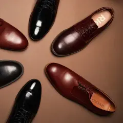 Eleganckie brązowe buty do czarnego garnituru i czarne lakierki, obie pary od Ryłko, ułożone na brązowym tle.