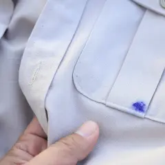 Niefortunna plama z atramentu na jasnej koszuli, tuż obok kieszeni.