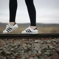 Białe adidasy Superstar to idealne buty do legginsów, świetnie wyglądają na tle torów kolejowych i krajobrazu.