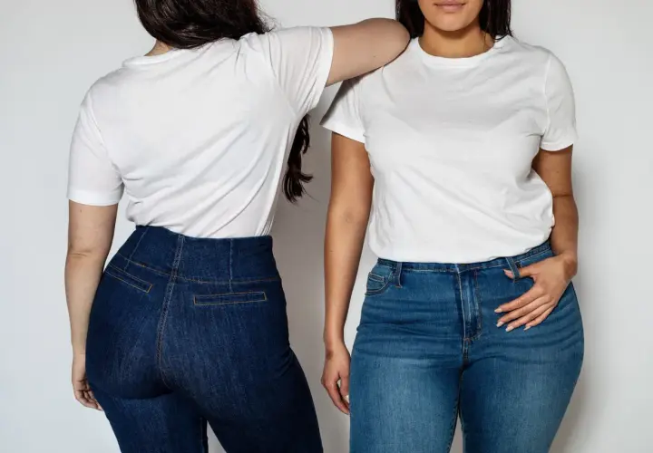 Dwie kobiety w białych T-shirtach i jeansach. Wysoki stan spodni to świetny sposób, jak ukryć brzuch w spodniach.