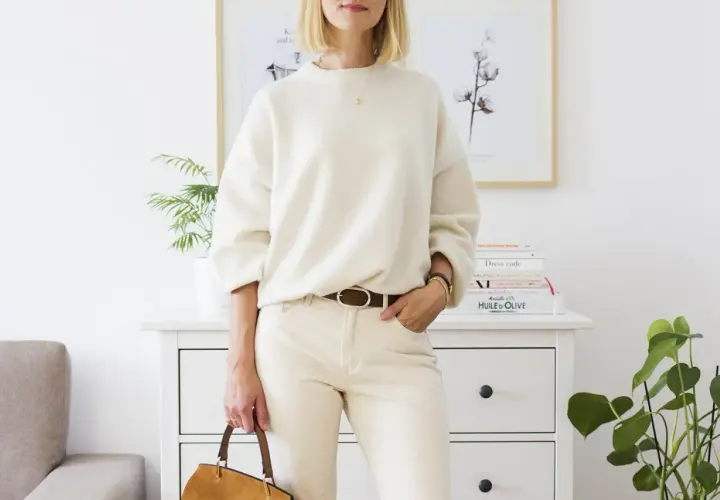 Eleganckie biały sweter stylizacje: luźny sweter, beżowe spodnie, brązowy pasek i torebka.