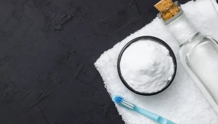 Soda oczyszczona w miseczce, butelka z płynem i szczoteczka do zębów na ręczniku. Idealne połączenie, by dowiedzieć się, czym zmyć trudne plamy.