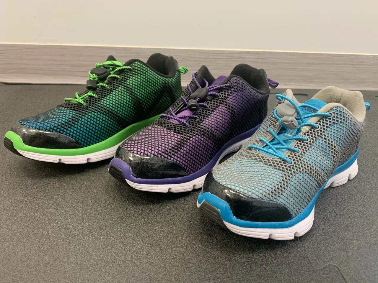 Trzy kolorowe buty sportowe z siateczką i sznurówkami. Idealne, gdy szukasz jakie buty na płaskostopie dla dorosłego.