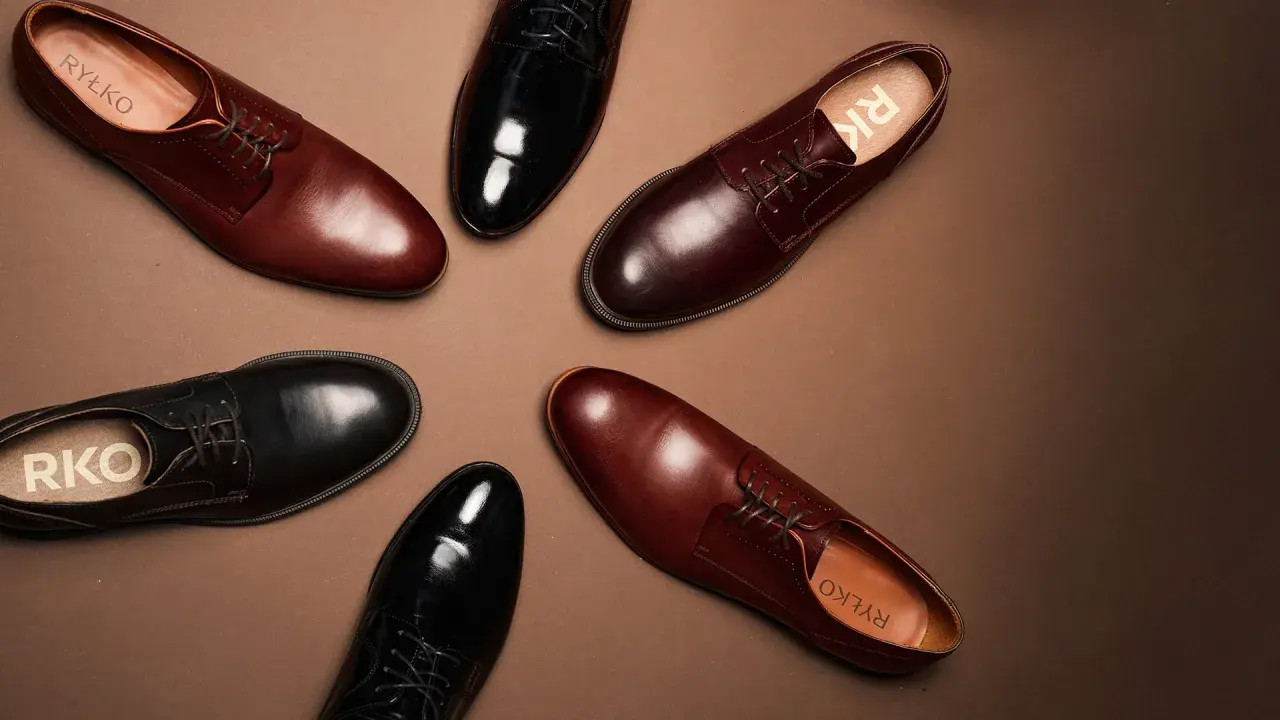 Eleganckie brązowe buty do czarnego garnituru i czarne lakierki, obie pary od Ryłko, ułożone na brązowym tle.